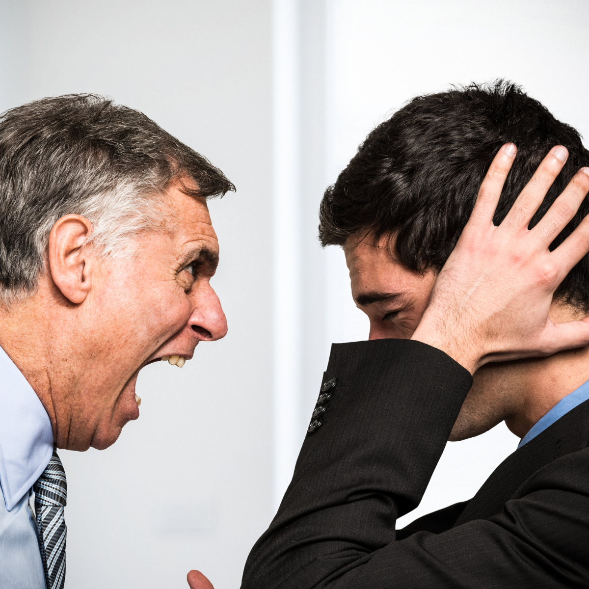 an angry boss screaming at a staff member who has his hands over his ears and looks scared